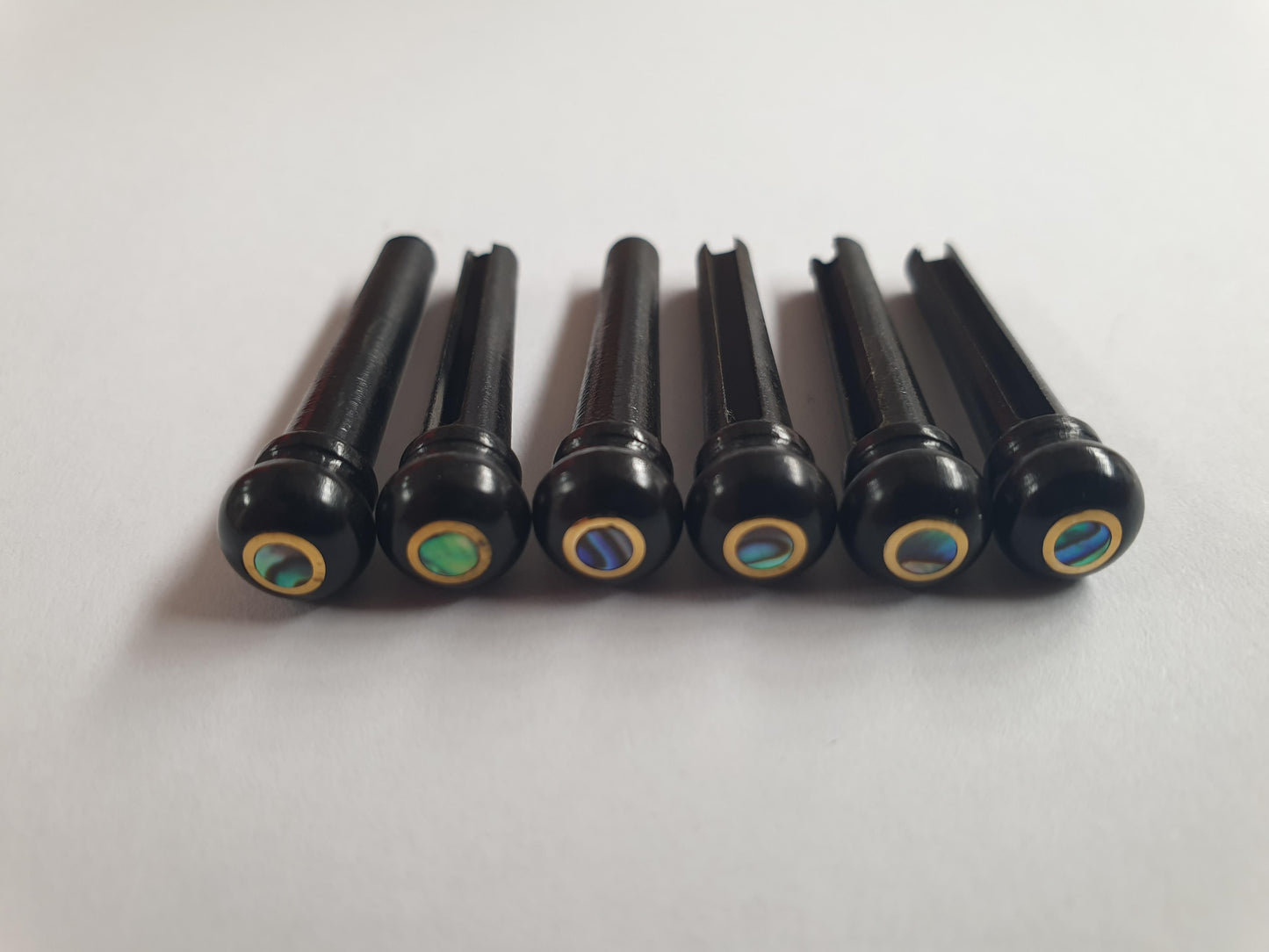 1 set (6pcs) Guitar bridge pins size 1 Ebony with brass ring and Paua dot Tapered shaft string slot running the full length of shaft. Diameter at top of shaft 5.3mm (0.21") length of shaft 22.9mm (0.9") . Will fit the following models - Martin guitars prior to 1994 (except HD-28), Collings guitars, prior to 2002, Blanchard, Garrison, Goodall, Ryan, Santa Cruz, Taylor, Larrivee D-03R and others.
