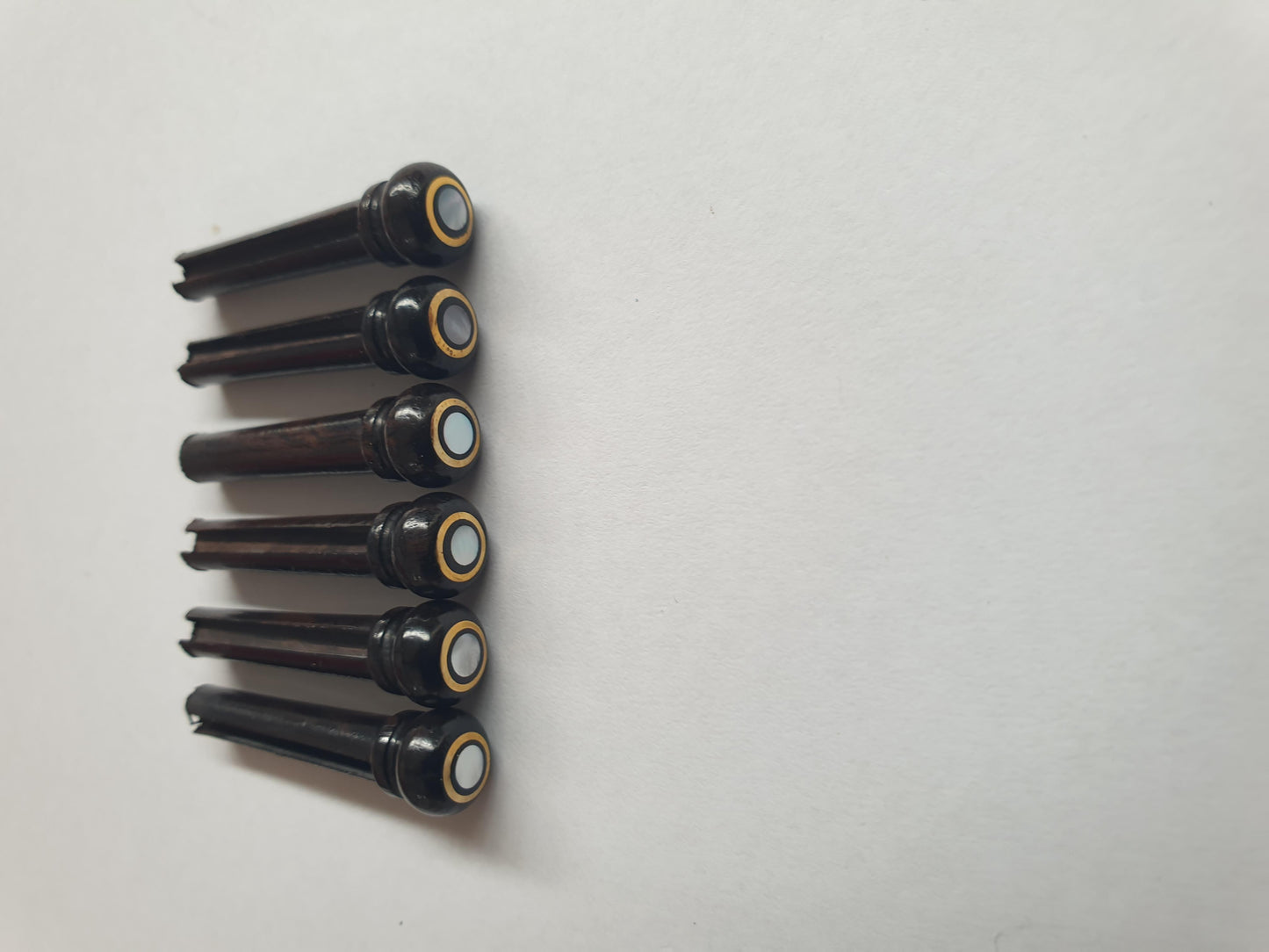 1 set (6pcs) Guitar bridge pins size 1 Ebony with brass ring and white mother of pearl dot Tapered shaft string slot running the full length of shaft. Diameter at top of shaft 5.3mm (0.21") length of shaft 22.9mm (0.9") . Will fit the following models - Martin guitars prior to 1994 (except HD-28), Collings guitars, prior to 2002, Blanchard, Garrison, Goodall, Ryan, Santa Cruz, Taylor, Larrivee D-03R and others.