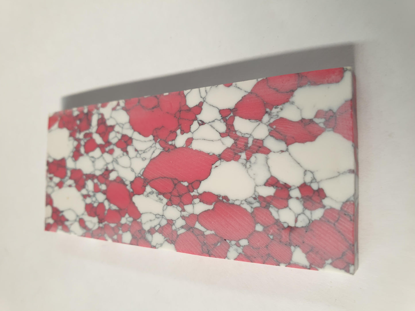 Kakortokite E38 artificial stone blanks 37 x 90 x 4.76mm suitable for inlay, knife handle scales. Can be cut with standard cutting tools - jewellery saw similar in characteristics to mother of pearl (hardness approx. 3. Can be sanded and polished same way as shell material. All pcs are A grade good on both sides.