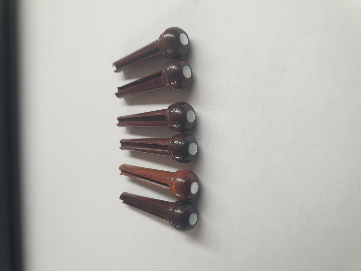 1 set (6pcs) Guitar bridge pins size 2A Rosewood with White Mother of Pearl dot. Tapered shaft string slot running the full length of shaft. Diameter at top of shaft 5.6mm (0.22") length of shaft 25.5mm (1") . Will fit the following models - Martin guitars since 1994,as well as D-28 older Gibson guitars,and others.