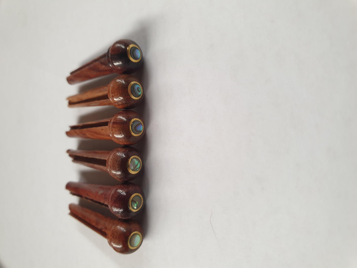 1 set (6pcs) Guitar bridge pins size 2A Rosewood brass with Paua dot. Tapered shaft string slot running the full length of shaft. Diameter at top of shaft 5.6mm (0.22") length of shaft 25.5mm (1") . Will fit the following models - Martin guitars since 1994,as well as D-28 older Gibson guitars,and others.