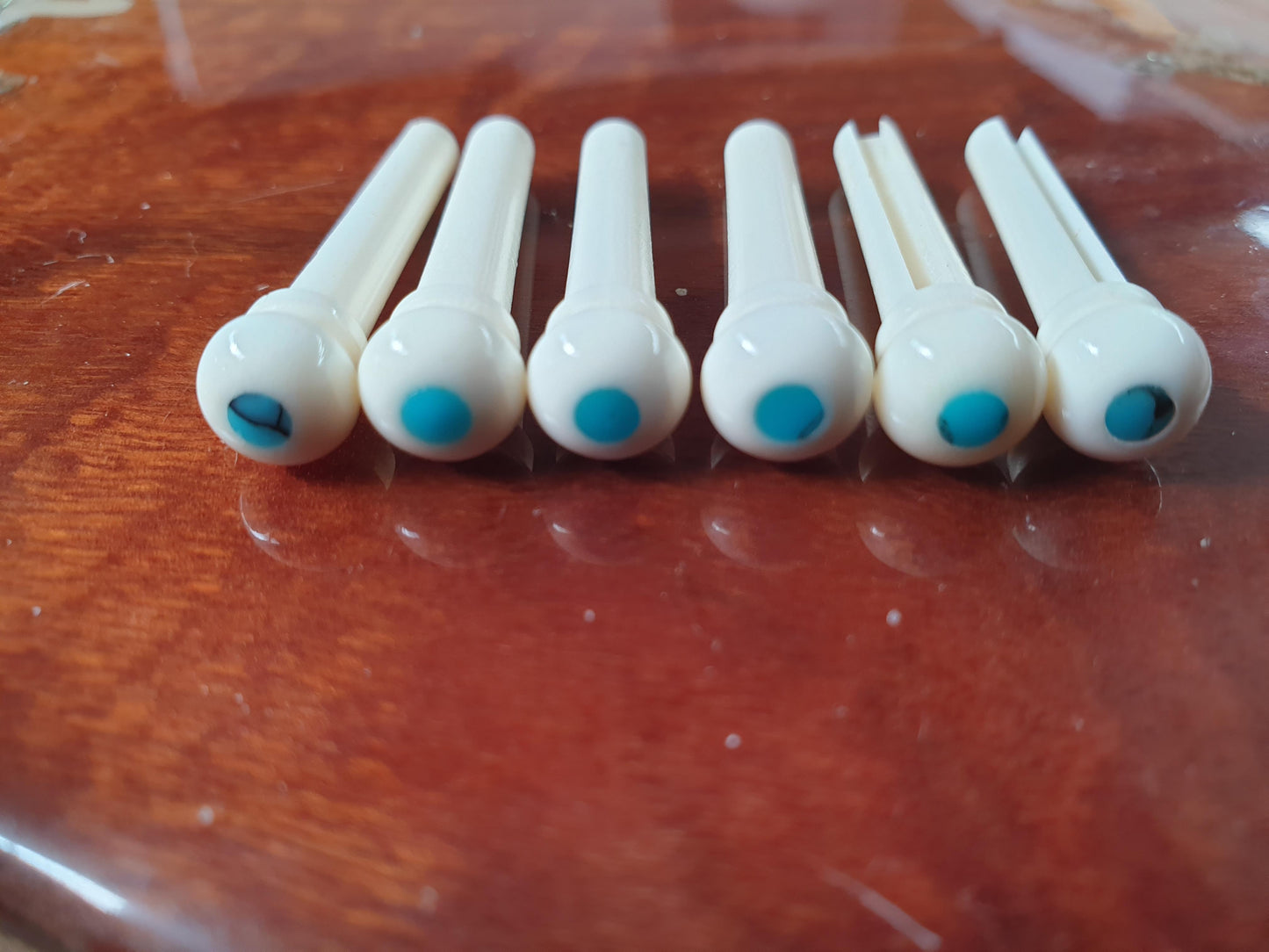 1 set (6pcs) Guitar bridge pins size 1 white bone with Turquoise dot Tapered shaft string slot running the full length of shaft. Diameter at top of shaft 5.3mm (0.21") length of shaft 22.9mm (0.9") . Will fit the following models - Martin guitars prior to 1994 (except HD-28), Collings guitars, prior to 2002, Blanchard, Garrison, Goodall, Ryan, Santa Cruz, Taylor, Larrivee D-03R and others.