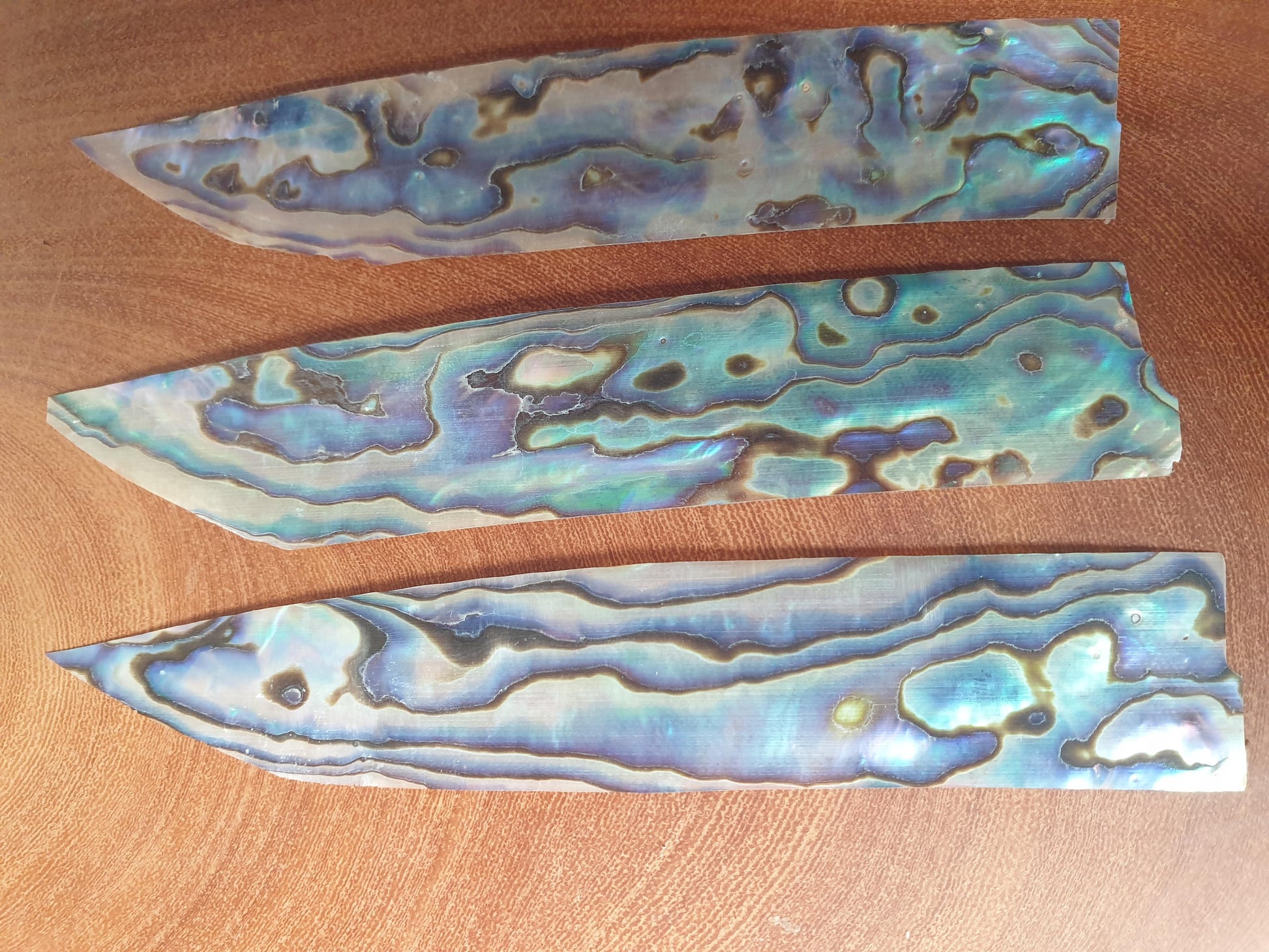 <p>Paua shell feathers 25-30mm (1-1.2") width x 90-115mm (3.5-4.5") length x 0.15mm (0.006") thickness - thinly sliced solid shell pcs. Cut along the curved part of shell they can yield larger pcs then standard solid shell blanks. Ideal for shallow inlay, overlay, fishing lure manufacture and other decorative purposes.</p>