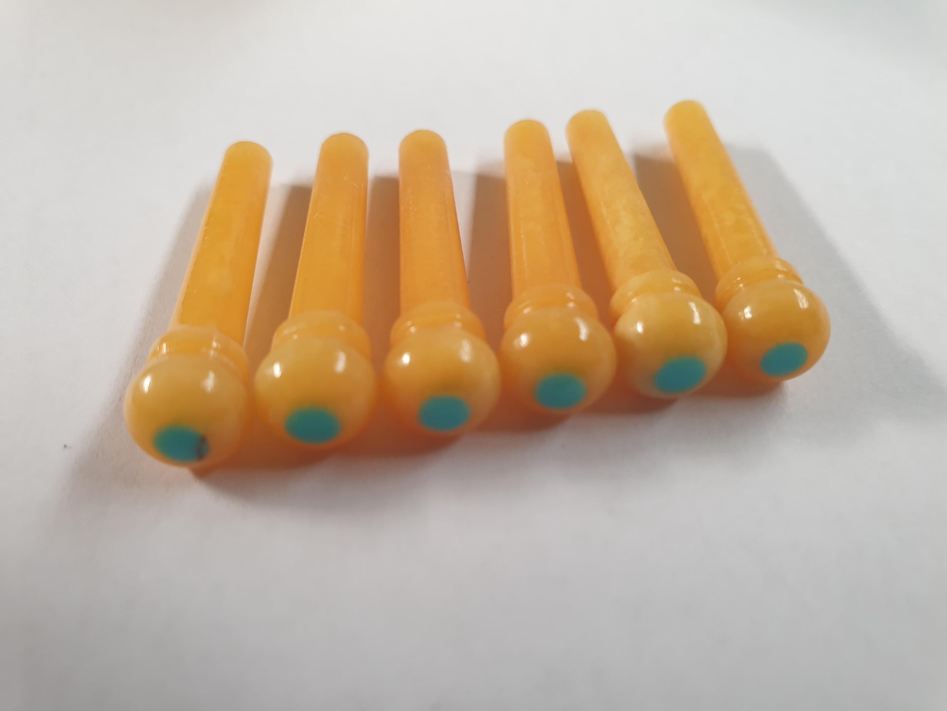 1 set (6pcs) Guitar bridge pins size 1 vintage bone with Turquoise dot  Tapered shaft string slot running the full length of shaft. Diameter at top of shaft 5.3mm (0.21") length of shaft 22.9mm (0.9") . Will fit the following models - Martin guitars prior to 1994 (except HD-28), Collings guitars, prior to 2002, Blanchard, Garrison, Goodall, Ryan, Santa Cruz, Taylor, Larrivee D-03R and others.