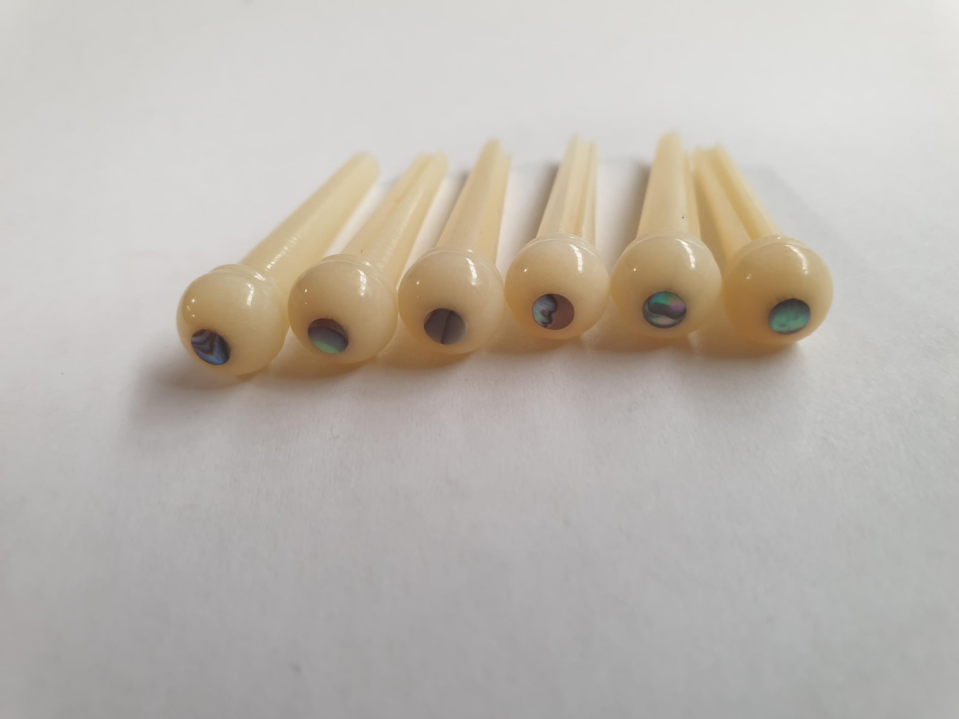 1 set (6pcs) Guitar bridge pins  size 2A Vintage bone with Paua dot. Tapered shaft string slot running the full length of shaft. Diameter at top of shaft 5.6mm (0.22") length of shaft 25.5mm (1") . Will fit the following models - Martin guitars since 1994,as well as D-28 older Gibson guitars,and others.